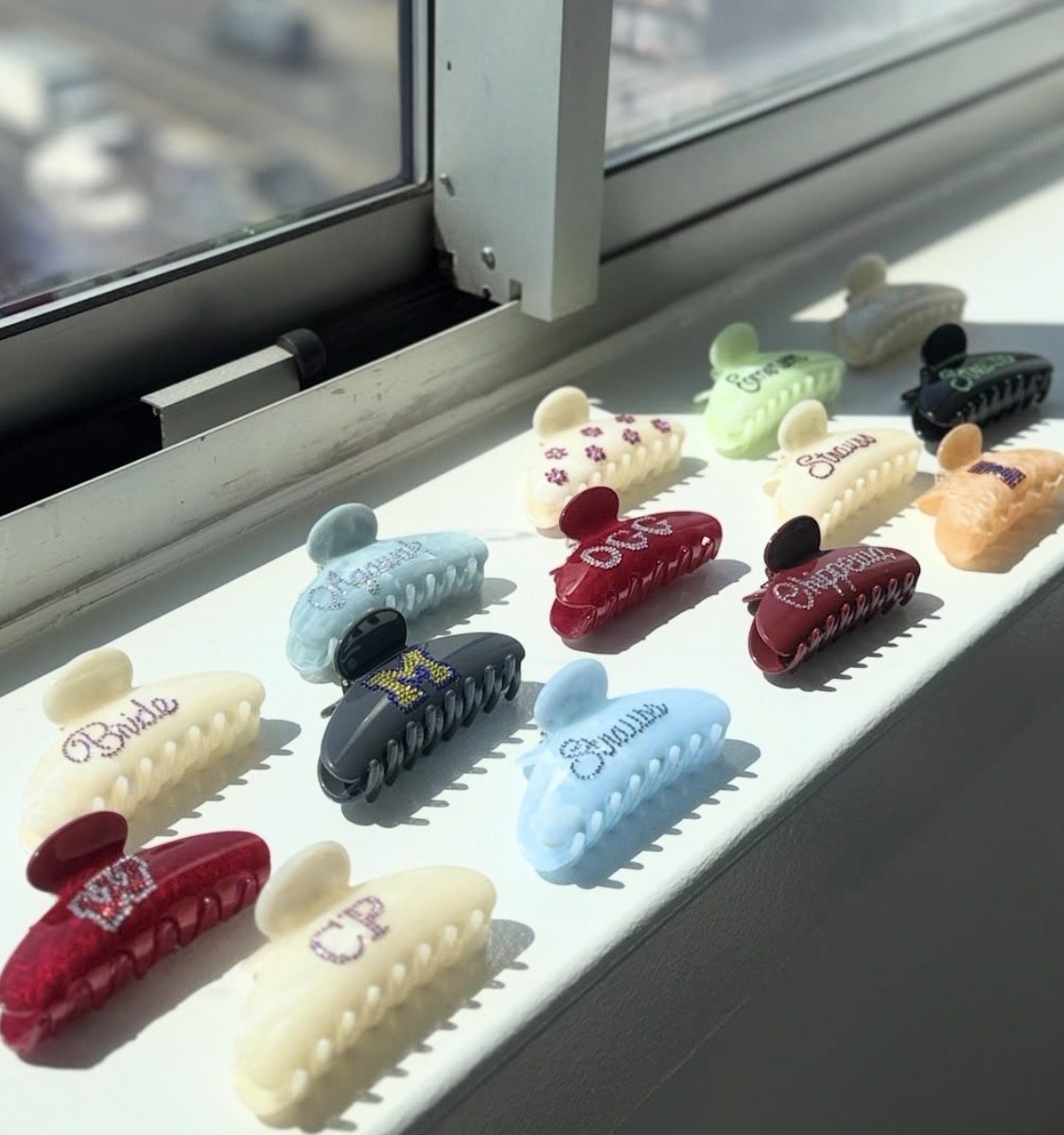 a windowsill lined with personalized rhinestone claw clips